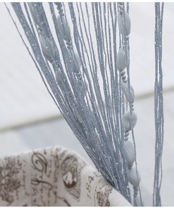 Macro shot of light blue tassel curtain featuring olive-shaped beads and silver glitter