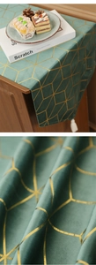 Détail du chemin de table en velours vert foncé avec motifs géométriques dorés et pompons blancs
