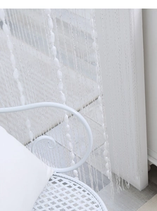 Detail of white string curtain with beads, showing elegant texture and semi-transparent design