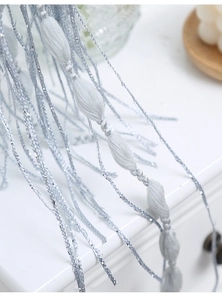 Close-up of silver-blue woven fringe curtain with metallic fiber and olive-shaped knots