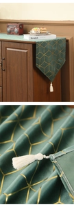 Détail du chemin de table en velours vert foncé avec motifs géométriques dorés et pompons