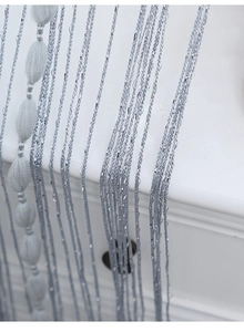 Detail of light blue string curtain with silver tinsel and grey velvet beaded tassels