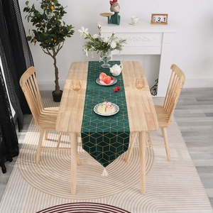 Détail d'un chemin de table vert foncé avec motif nid d'abeille doré et pompons blancs