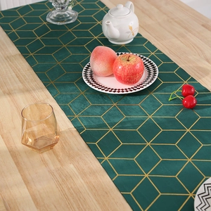 Vue détaillée du chemin de table en velours vert foncé avec motifs géométriques dorés