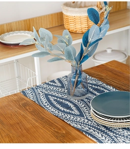 Detailed view of navy blue and white geometric leaf pattern woven table runner on wood