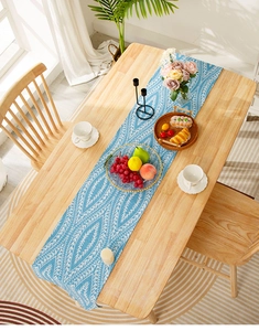 Detailed texture of light blue linen table runner with white leaf and geometric patterns