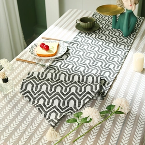 Linen table runner with black and white geometric wave patterns and tassel details