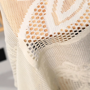Gros plan d'une nappe en dentelle beige révélant des motifs de maille et de tissage nid d'abeille