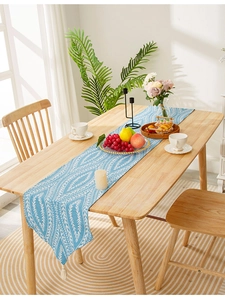 Blue and white leaf pattern table runner with tassels on a wooden dining table