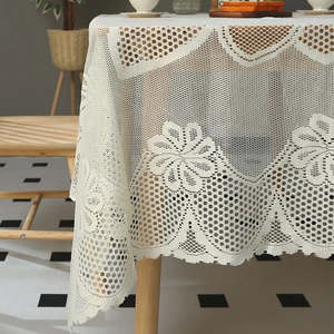 Vue détaillée de la nappe en dentelle blanche avec motifs floraux et texture en maille