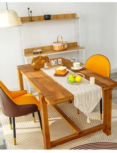 Detail of cream table runner with botanical leaf patterns and elegant tassel trim on wood table