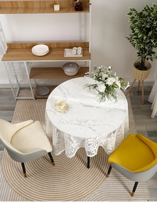 Close-up of white round lace tablecloth with floral hollow patterns on a dining table