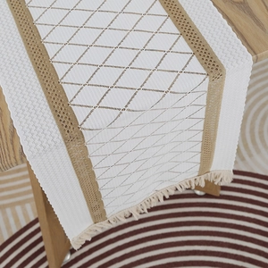 Detail of bohemian table runner with beige geometric crochet patterns and fringe edges