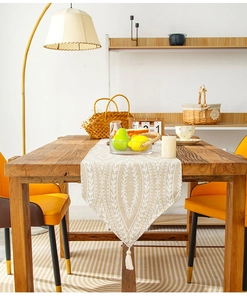 Close-up of beige linen table runner with white wheat pattern and tassel fringe detail