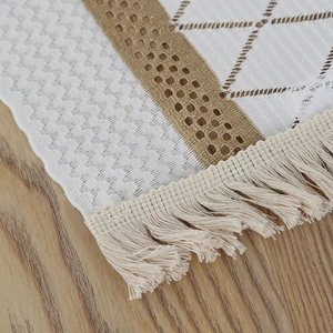Detail of boho table runner featuring beige crochet patterns and rich fringe tassels