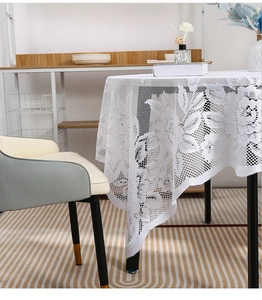 Detailed close-up of white lace tablecloth with floral hollow patterns and elegant drape