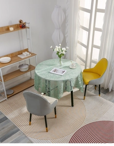 Detail of light green lace round tablecloth with intricate floral cutout on a wooden table