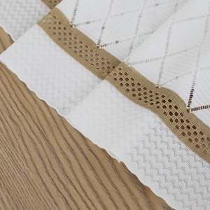 Close-up of white diamond knit fabric with khaki hollow lace trim on wooden background