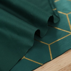 Détail macro du chemin de table vert foncé avec broderie géométrique hexagonale dorée