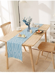 Close-up of blue textured table runner with white leaf patterns and fringe tassels