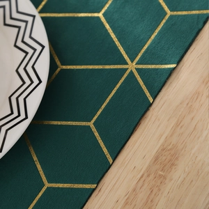 Détail du chemin de table vert foncé avec motif hexagonal doré sur une table en bois