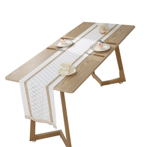 Modern table runner with diamond grid pattern and tassels on a wooden dining table