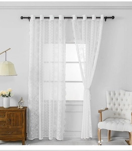 Dettaglio tenda in pizzo bianco con delicati motivi floreali traforati e occhielli metallici