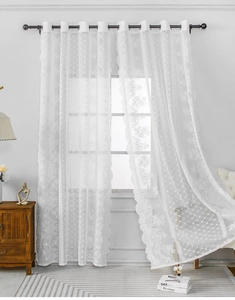 Dettaglio tenda in pizzo bianco con ricamo floreale e bordi ondulati a onde