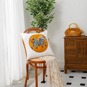 Square throw pillow with zebra and elephant print on white fabric with yellow piping