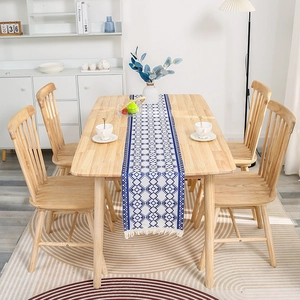 Blue and white geometric cotton linen table runner with white tassels on a wooden table