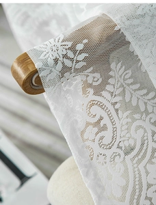 Dettaglio ravvicinato del tessuto in pizzo floreale bianco con maglia e bordi sagomati
