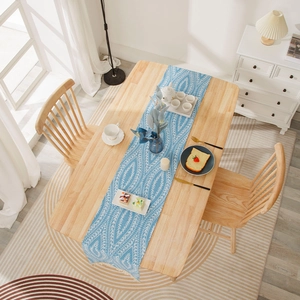 Modern light blue table runner with white leaf patterns and tassels on a wooden table