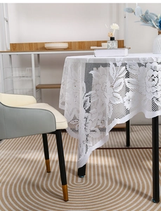 Detailed view of white floral lace tablecloth with elegant scalloped edges in a home setting