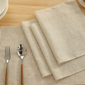 Beige linen rectangular placemat set with lock-stitch edges on a light wooden table