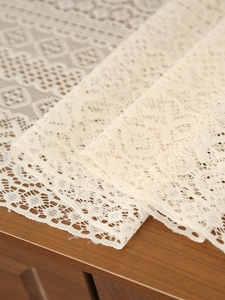 Detailed macro view of cream crochet lace runner with floral hollow patterns