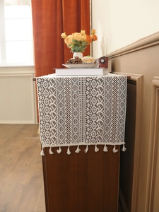 Close-up of vintage beige crochet table runner with hollow lace patterns and tassels