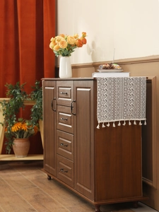 Detail view of a vintage dark brown wooden sideboard with black handles in a cozy home setting