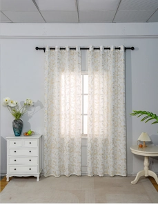 Detail view of white curtains with gold floral patterns and metal grommet top design