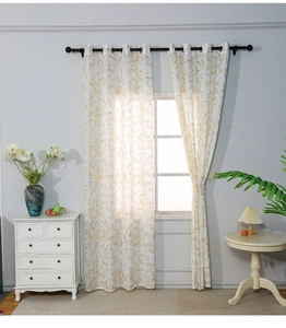 Detailed view of white blackout curtains with elegant gold floral prints and metal rings