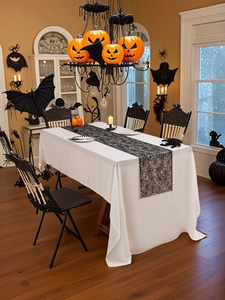 Detail of Halloween spider web lace table runner over white tablecloth with pumpkin decor