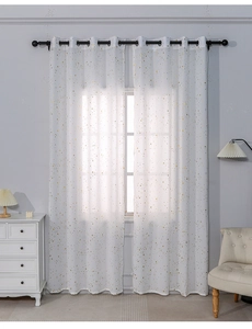 Detail of white semi-sheer curtains with gold star prints and metal grommets in living room
