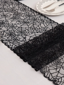 Detailed view of black lace Halloween table runner featuring intricate spider web patterns