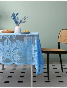 Close-up of sky blue knitted lace tablecloth with floral hollow patterns and wavy edges