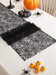 Detail view of black lace spider web table runner with Halloween pumpkin decorations