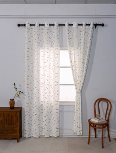 Close-up of white sheer curtain with golden feather prints and black metal eyelets