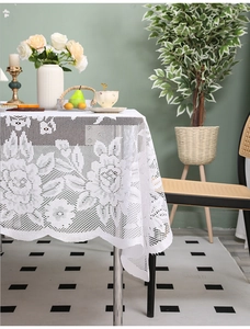 Close-up of white crochet lace tablecloth with vintage rose floral patterns and wavy edges