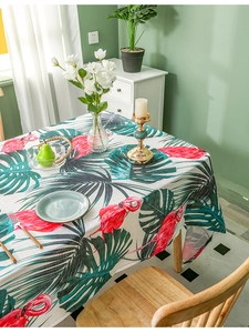 Detail of linen tablecloth with tropical flamingo and palm leaf print on a dining table