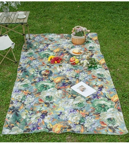 Detailed view of an oil painting style picnic blanket with floral print on green grass