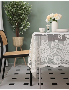 Close-up of white lace tablecloth with floral patterns and delicate scalloped edges
