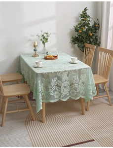 Detail of light green hollow lace tablecloth with floral patterns and wavy edges